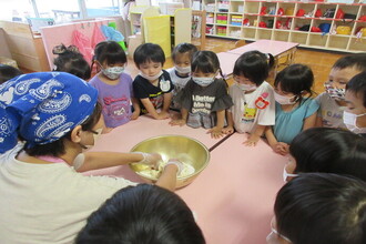 教師がつくる月見団子を見る園児